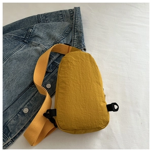 Detail view of a yellow waterproof nylon chest bag on a blue denim jacket background