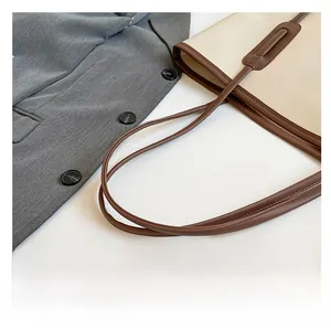 Close-up of comfortable brown shoulder strap attachment on beige tote bag detail