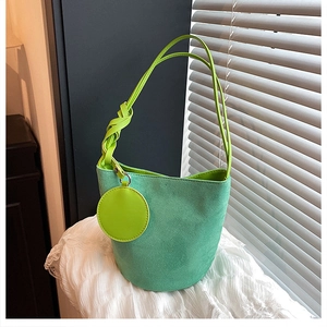 Détail du sac seau en daim vert avec porte-monnaie rond et poignée nouée