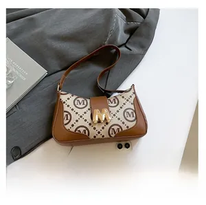 Detail of canvas underarm bag with monogram print and golden M-shaped metal buckle