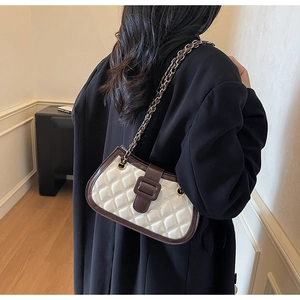 Borsa a tracolla trapuntata con catena indossata da una modella in interno moderno