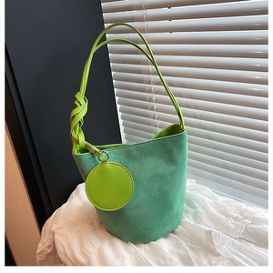 Détail du sac seau en daim vert foncé avec breloque porte-monnaie vert fluo