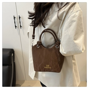 Sac seau marron à texture plissée et boucles argentées porté par un mannequin