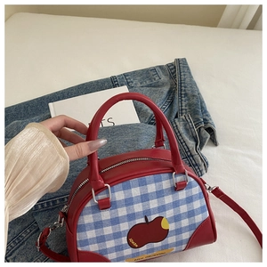 Close-up of red plaid Boston bag with apple patch and adjustable leather strap