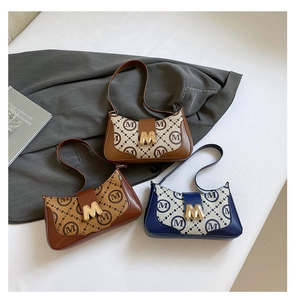 Three vintage baguette bags with letter pattern and metallic M-buckle on grey suit background