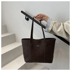 Détail d'un sac cabas marron vintage en cuir avec lettrage doré et longues bandoulières