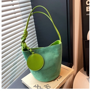 Détail du sac seau en daim vert avec pendentif rond et fine bandoulière