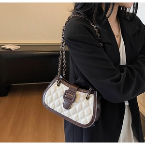 Close-up of quilted chain bag featuring cream leather and brown trim on a model