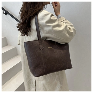 Vue latérale du grand sac cabas en cuir marron foncé avec logo doré et design épuré