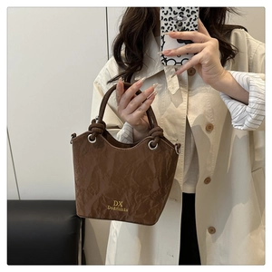 Gros plan du sac seau plissé marron avec logo doré et détails de poignée nouée