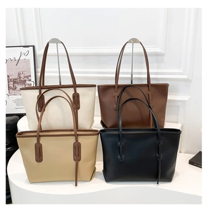 Detail view of large capacity tote bags in four neutral colors on a white display stand