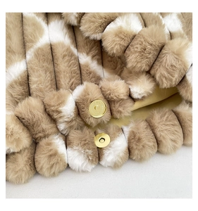 Detail of plush striped tote bag featuring golden metal magnetic clasps and soft texture