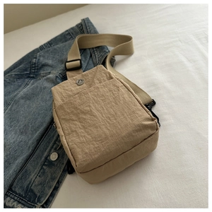 Close-up of beige nylon chest bag with adjustable strap and buckle on denim jacket