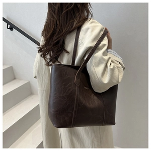 Grand sac cabas vintage marron porté avec un trench-coat dans un décor minimaliste