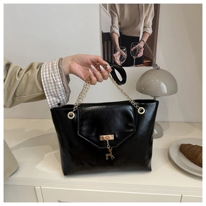 Close-up of black PU leather tote bag featuring golden hardware and deer charm detail