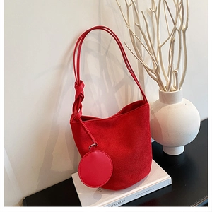 Détail d'un sac hobo en daim rouge avec bandoulière à nœud et mini breloque circulaire