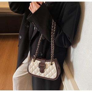 Dettaglio della borsa a tracolla trapuntata beige con finiture in pelle marrone e catena