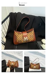 Detail view of vintage brown underarm bag with gold M buckle and logo canvas texture