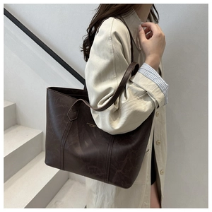 Détail du sac cabas marron foncé à texture vintage sur trench-coat beige