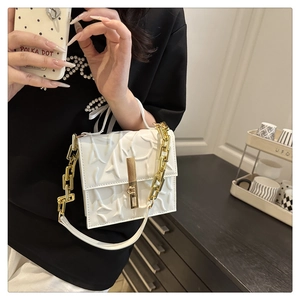 Close-up of white embossed leaf pattern bag with gold chain strap and metal lock