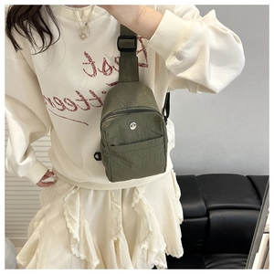 Olive green nylon chest bag with adjustable strap worn by model in daily life