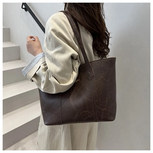 Mannequin portant un grand sac cabas vintage en similicuir marron foncé avec logo