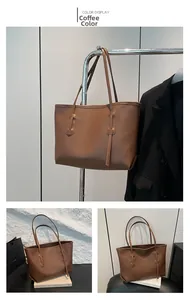 Detail view of large dark brown leather tote bag with stylish shoulder straps and charm