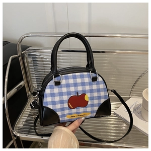 Detail of blue plaid canvas bag with red apple print and black leather handles