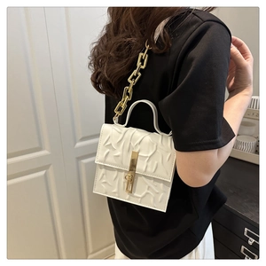 Modern white square handbag with embossed texture and gold chain strap on model