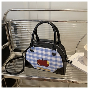 Detailed view of checkered handbag featuring red apple print and black handles