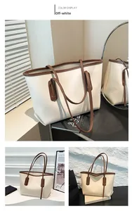 Detail view of large beige tote bag with brown straps in a minimalist indoor setting