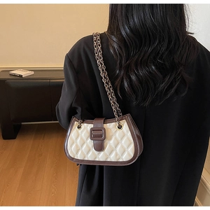 Close-up of quilted lattice shoulder bag with brown trim and metal leather chain strap