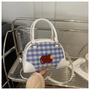 Detail of blue gingham bowling bag with red apple print and white leather trim