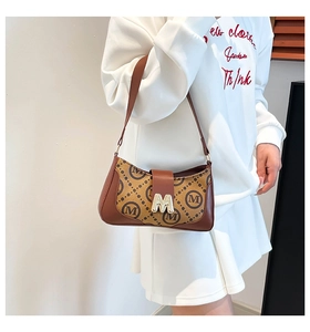 Detail of vintage baguette bag with brown M-pattern print and gold metal buckle