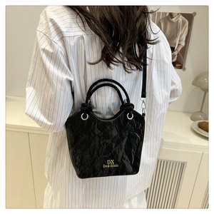 Détail du sac seau noir plissé avec lettrage doré et anneaux métalliques argentés