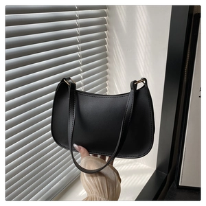 Minimalist black matte underarm bag featuring sleek curved lines and gold metal rings