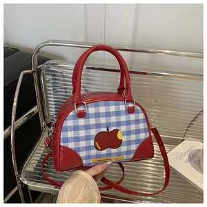 Detail of checkered apple crossbody bag with red PU leather handle and metal accents