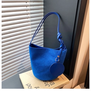 Détail du sac seau bleu vif en velours avec bandoulière nouée et petit porte-monnaie