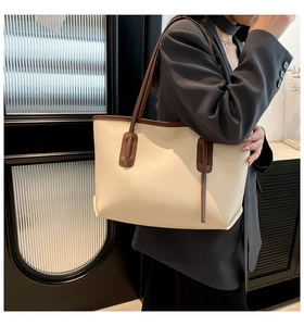 Large cream tote bag with brown handles styled on a shoulder in an office setting