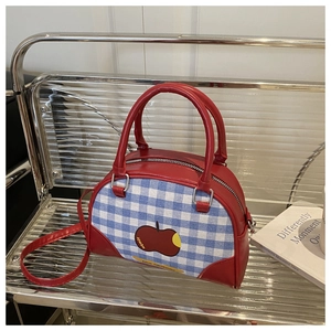 Detail of red Boston bag with blue-white checkered pattern and apple design