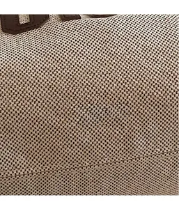 Close-up of beige woven canvas texture with brown leather stitching detail on tote bag