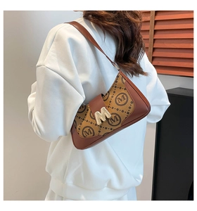 Detailed side view of vintage monogram shoulder bag with gold M buckle on a model