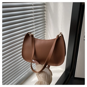 Detail of a brown crescent shoulder bag with golden buckle and sleek leather texture