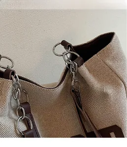 Detail of canvas tote bag showing silver metal rings and brown leather reinforced trim