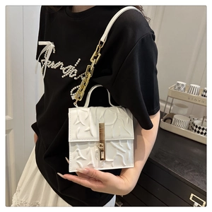Detail of white chain crossbody bag featuring unique embossed floral texture and gold clasp