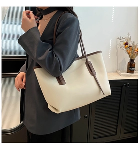 Detailed view of a large cream tote bag with dark brown handles worn by a model