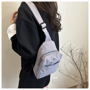 Detailed back view of a grey waterproof nylon chest bag worn by a model in soft light