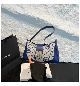 Detailed close-up of navy blue jacquard monogram bag with golden M-shaped metal buckle