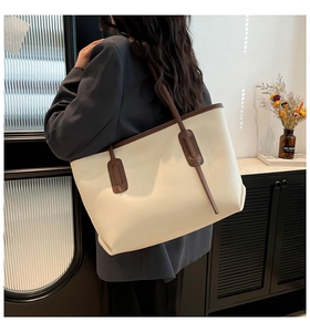 Minimalist large tote bag shown on shoulder with off-white matte finish and brown straps