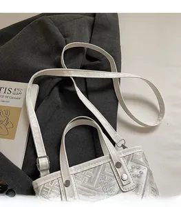 Detailed macro shot of white embroidered bucket bag with adjustable shoulder strap